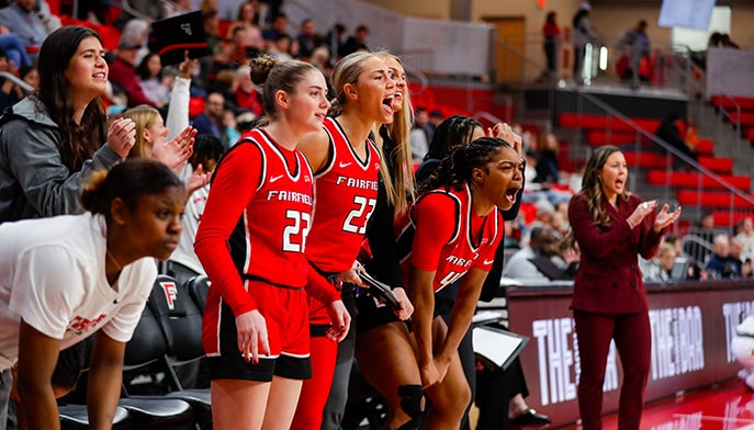 Sideline student-athletes yelling and cheering during a Women's Basketball game.