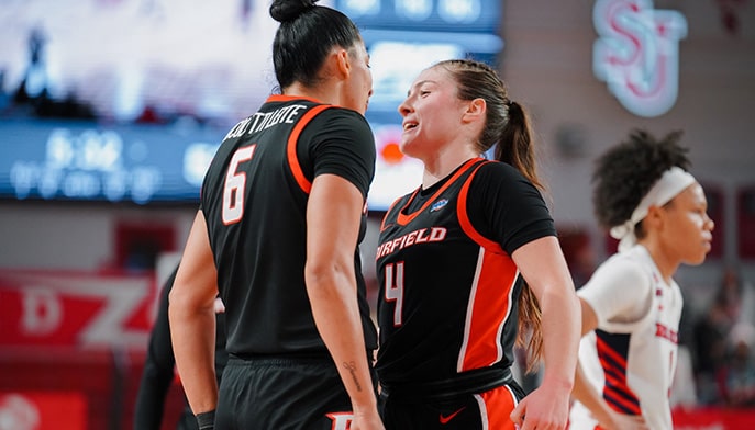 Women's Basketball players standing chest to chest as they hype one another up.