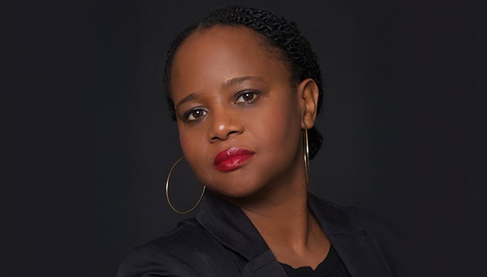 Portrait headshot of renowned novelist Edwidge Danticat on a dark black background.