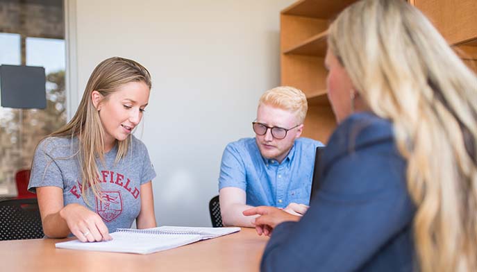 Image of students and professor sitting in office