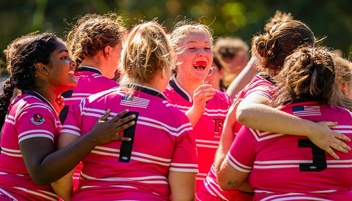 Fairfield Women's Rugby student-athletes huddling and celebrating a goal during RugbyFest.