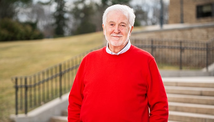 John Charles Meditz '70 dressed in a red sweater for his headshot portrait.