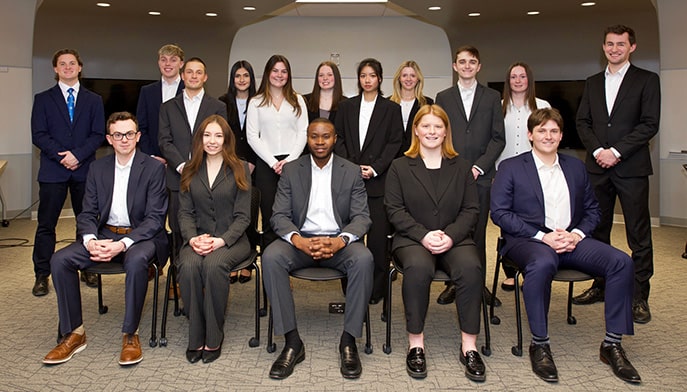 Business students, dressed in suits, posing for a group photo of the combined StartUp teams.