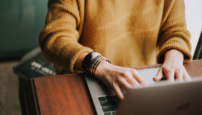 Someone sitting in a chair and typing on a laptop