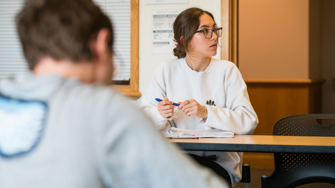 A student sits at a desk and looks forward.