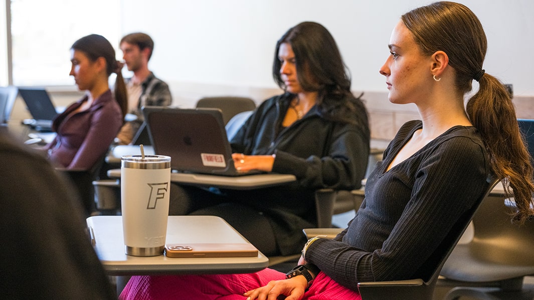 Students sit at desks in a classroom.