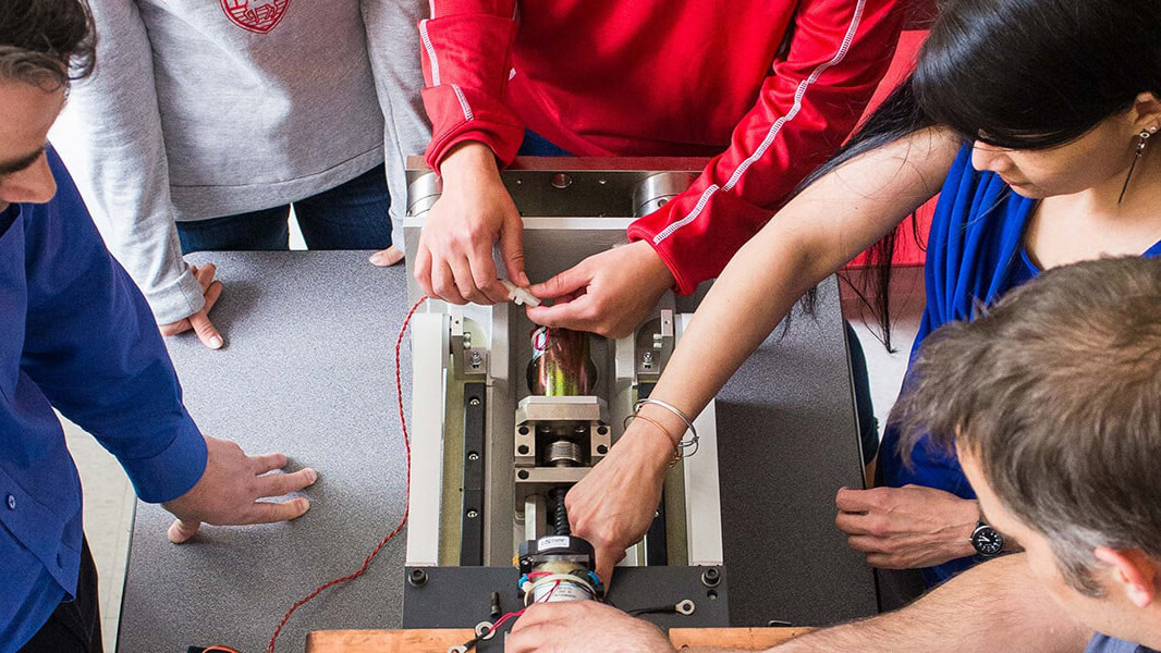 Mechanical Engineering students working on a small machine in a classroom. 