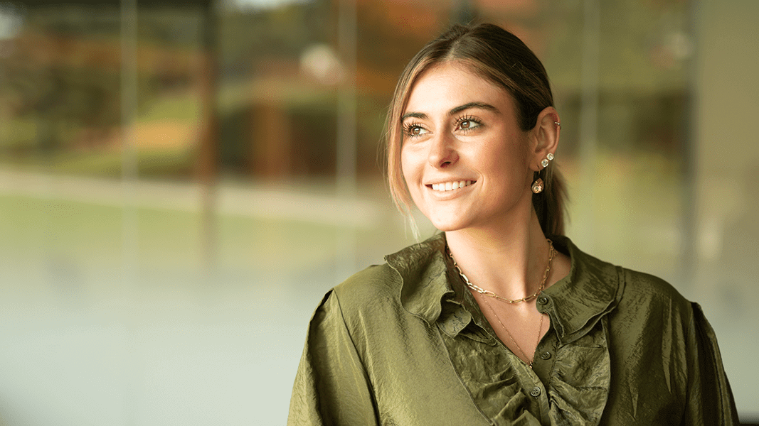 A student smiles in a green shirt.