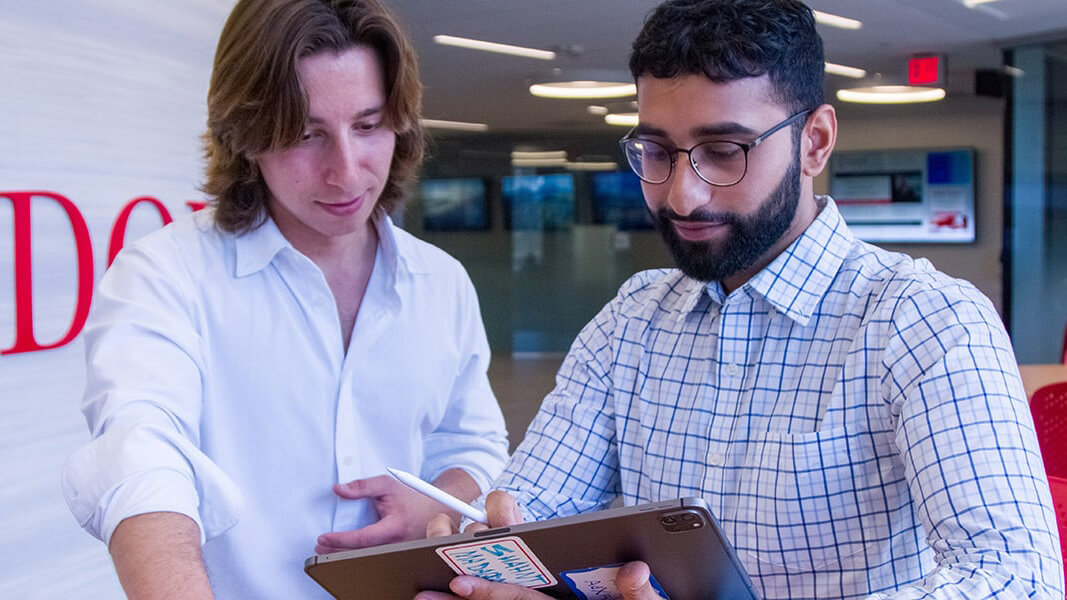 Two business students work together on an ipad in a common area of dolan school of business 