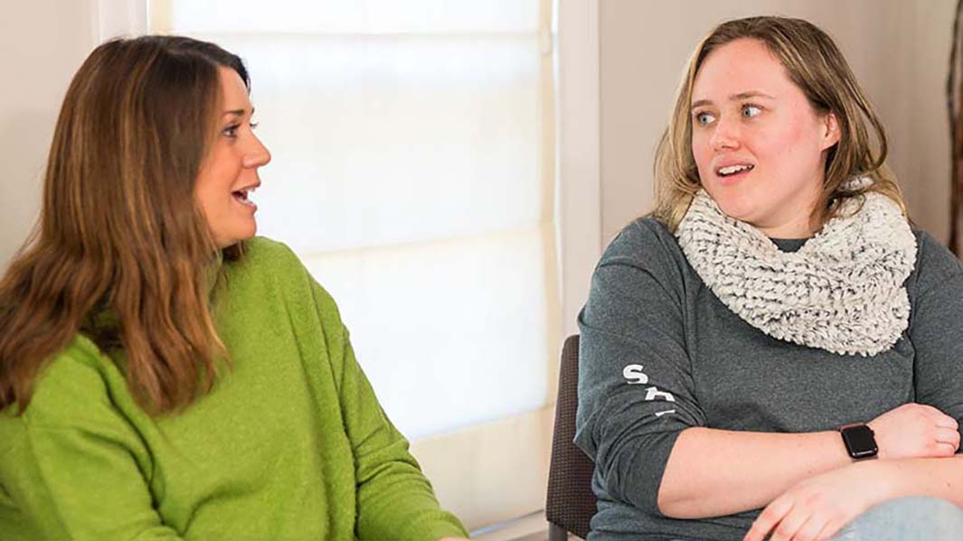 Two students sit and talk to each other.