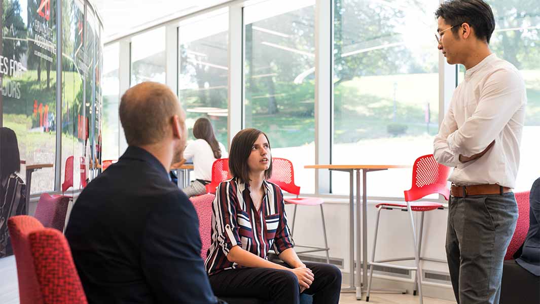 Two students sit and talk with a professor.