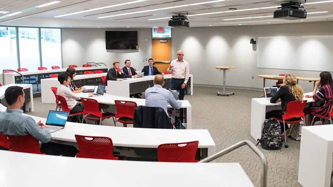 A classroom is full of students sitting at tiered desks.