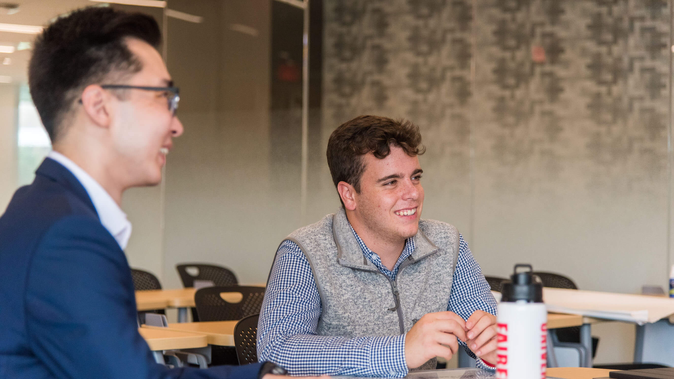 Two students laugh together at a table in dsb conference room.