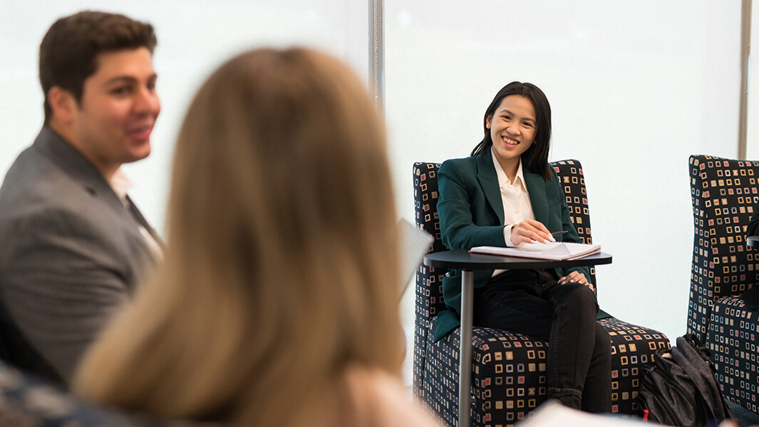 3 dsb students sitting down smile and talk in a common room.