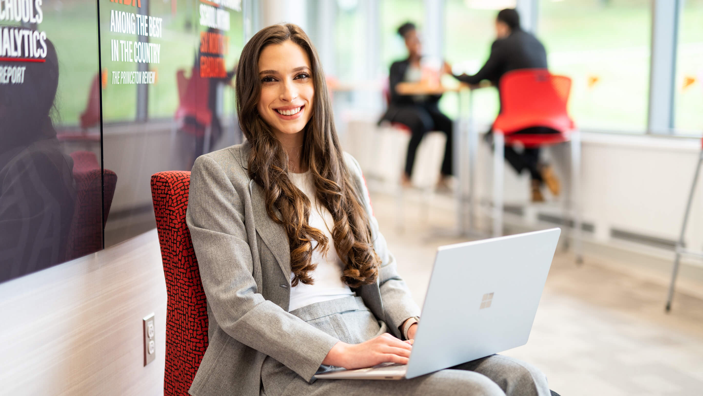 A student sits with a laptop on their lap.