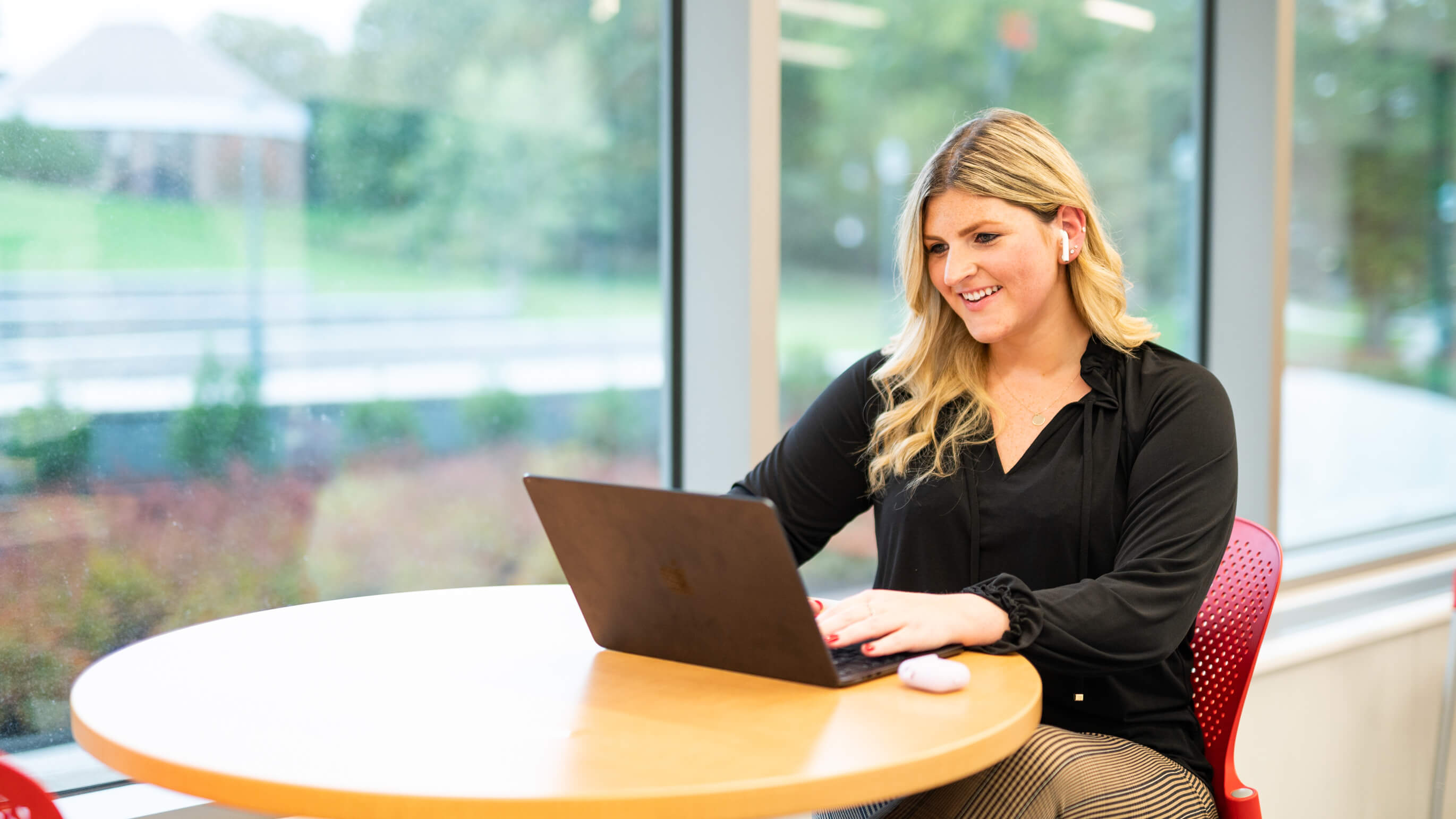 A student sits at a table using a laptop.