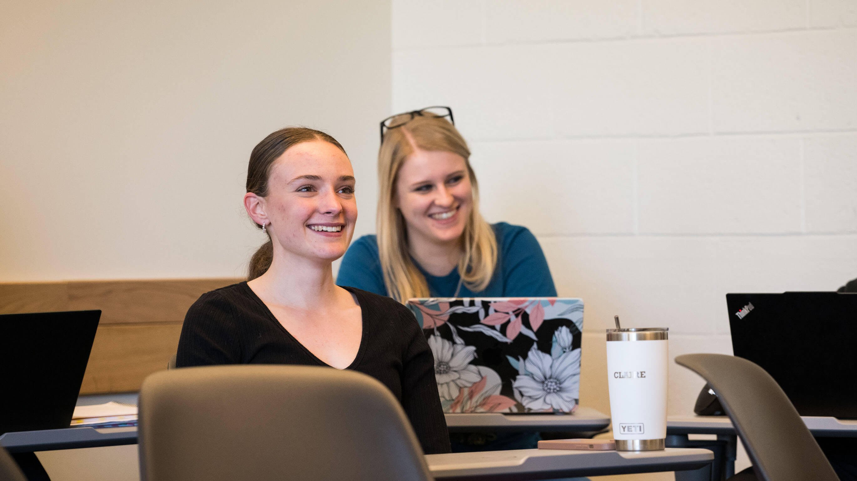 Two students smile in a classroom.