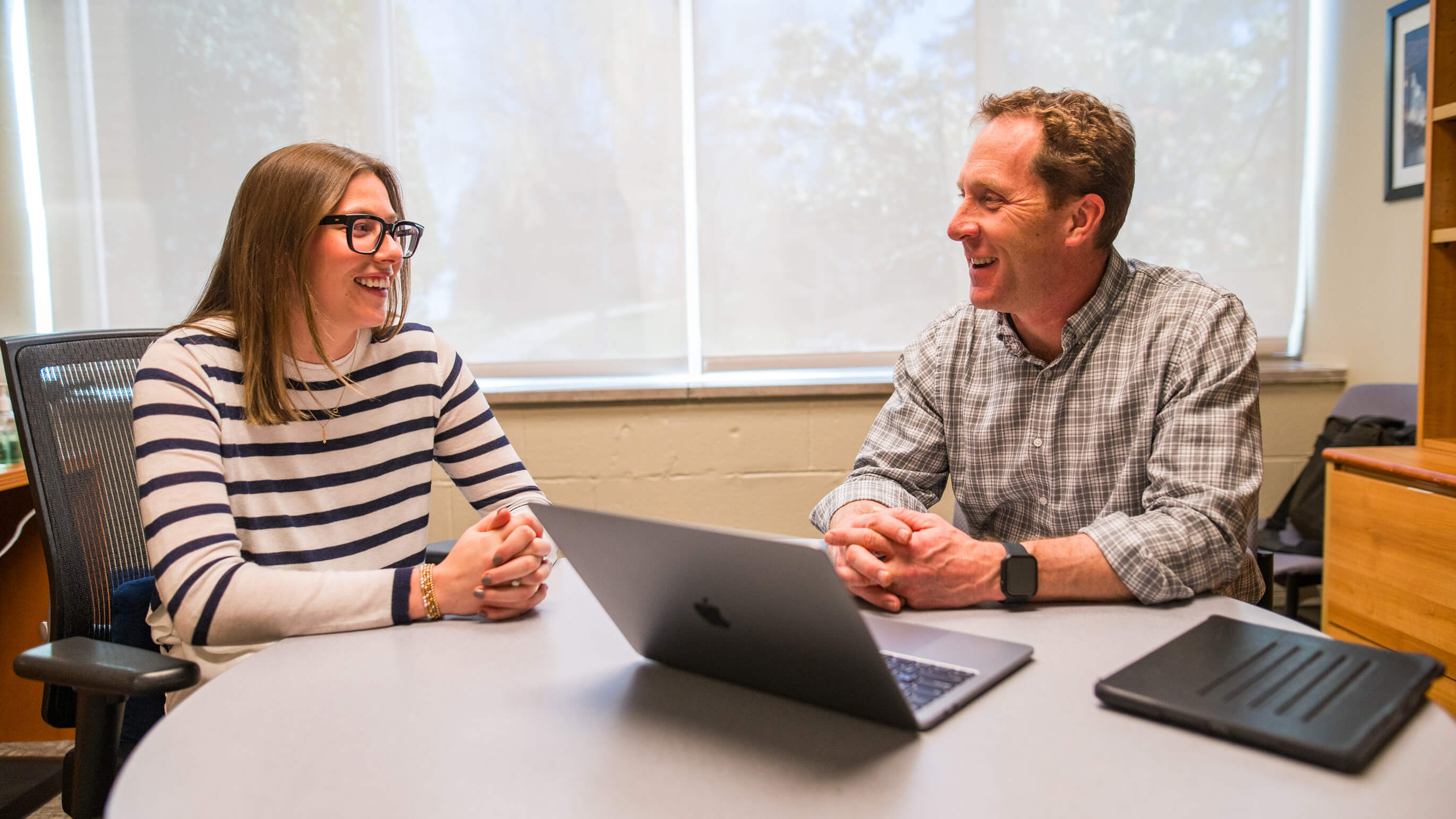 A professor and student sit at a table.