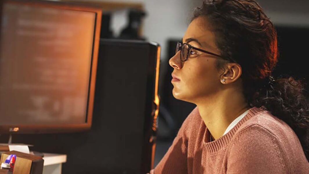 Cybersecurity student working at computer in the dark.