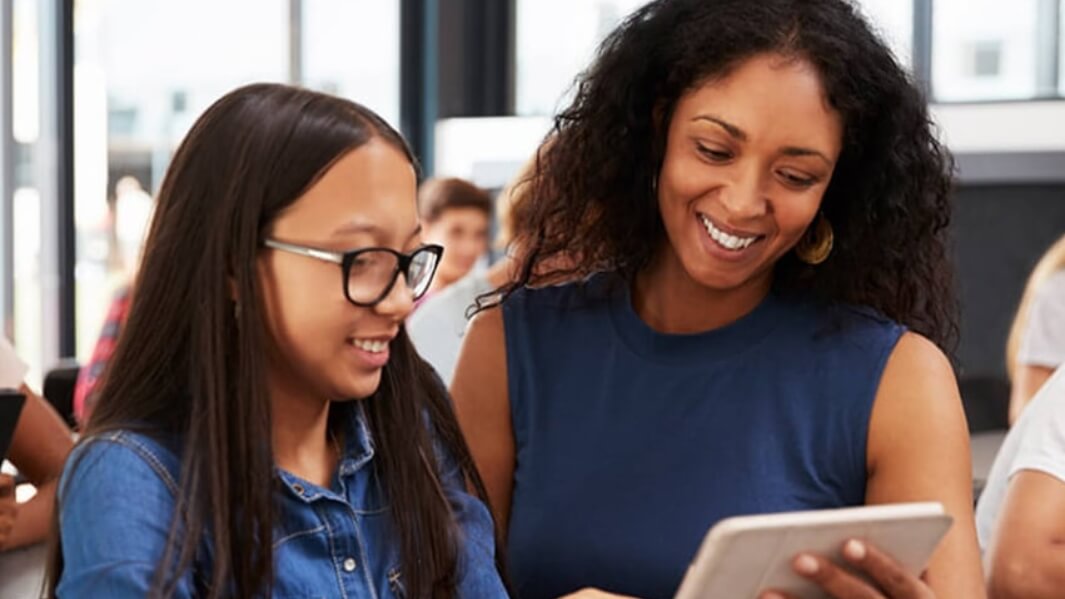 Student and professor looking at tablet in class.