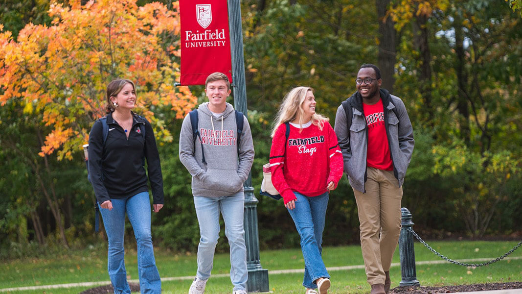 4 students walk together on campus in the fall.