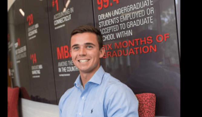 A dsb student smiles at camera with dsb stats behind him.