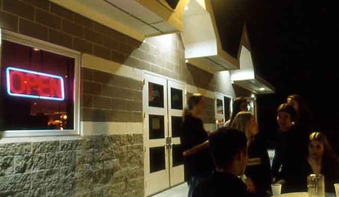 Exterior of Levee at night with students mingling on patio.