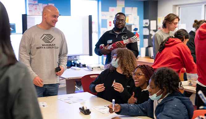  A classroom scene featuring a teacher and a group of attentive students collaborating on educational tasks.