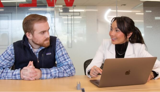 Two dolan students look at each other in a study space.