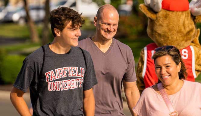 Student walking around campus with his parents. Lucas the stag is in the background. 