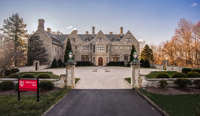 An exterior of a brick building with a road marked by a sign that reads “Bellarmine Hall”. 