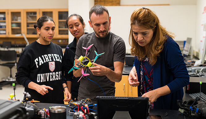 Three students and a professor work on a lab assignment.