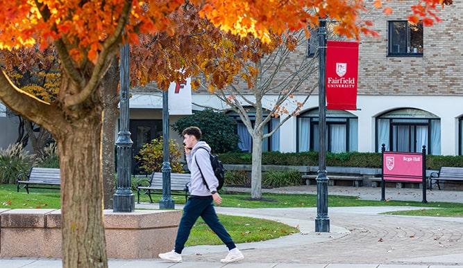 A student walking through campus on the phone alone on a fall day.