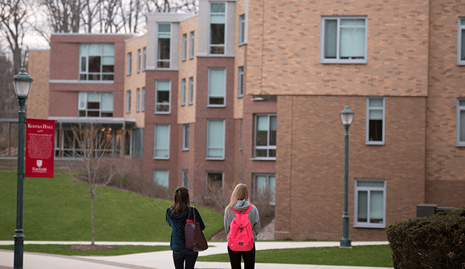 Two students walk towards dorm building on campus.