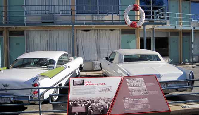 Two retro cars are parked behind a sign that reads “Here, on April 4, 1968…”.