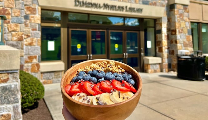 A student holds an acai bowl outside of the library.