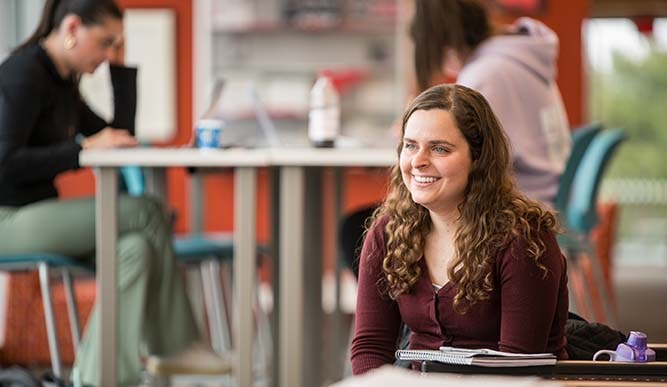 A student sits at a table in front of their notebook.