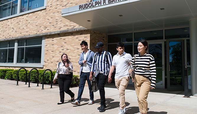 A group of students walk out of a building with a sign that reads “Rudolph F. Bannow Science Center”.