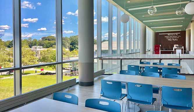 Tables in Fairfield Unviersit's Tully Dining Hall overlooking campus through large glass windows.