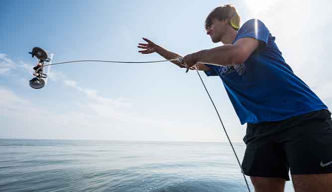 A man stands on the water, firmly holding a fishing rope, immersed in the peaceful activity of research.