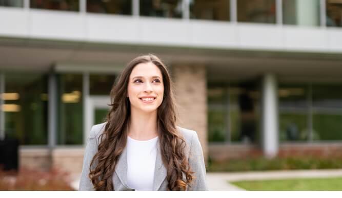 Smiling student in formal clothing walks in front of dsb.