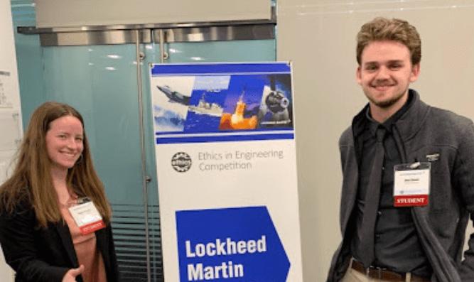 Two students standing by a Lockneed Martin Recruiting banner.