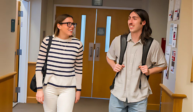 Two students walking through a hallway. 