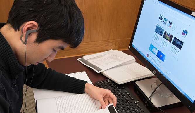 Student taking notes at computer.