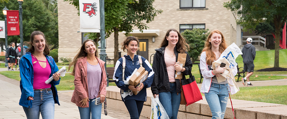 Image of Fairfield University students walking with mail and packages in hand