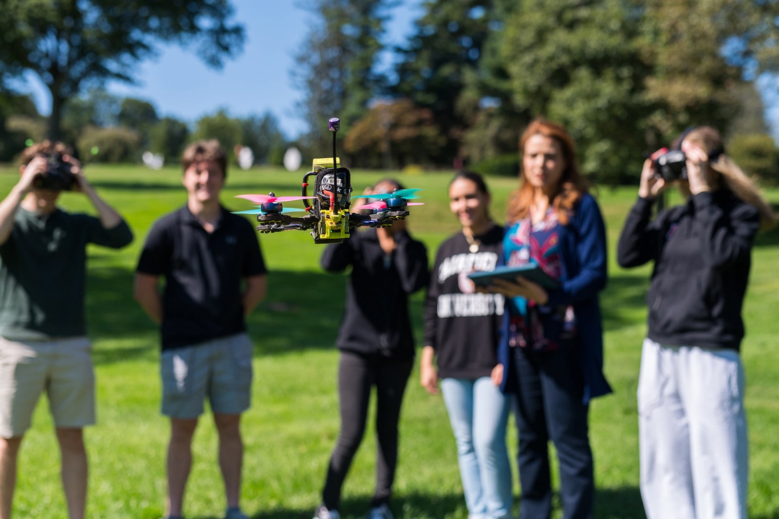 Selective focus shot of Fairfield University engineering students and faculty flying a drone.